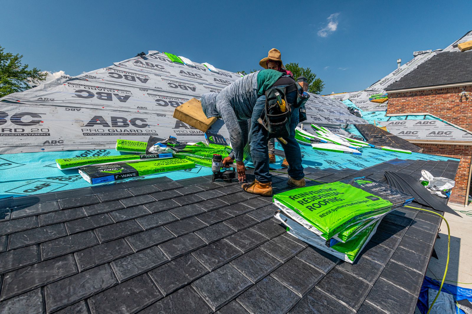 Crew installing a synthetic slate roof on a brick house in Fort Worth